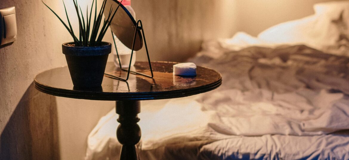 A warm, inviting bedroom with ambient lighting, soft linens, and stylish decor on a side table.