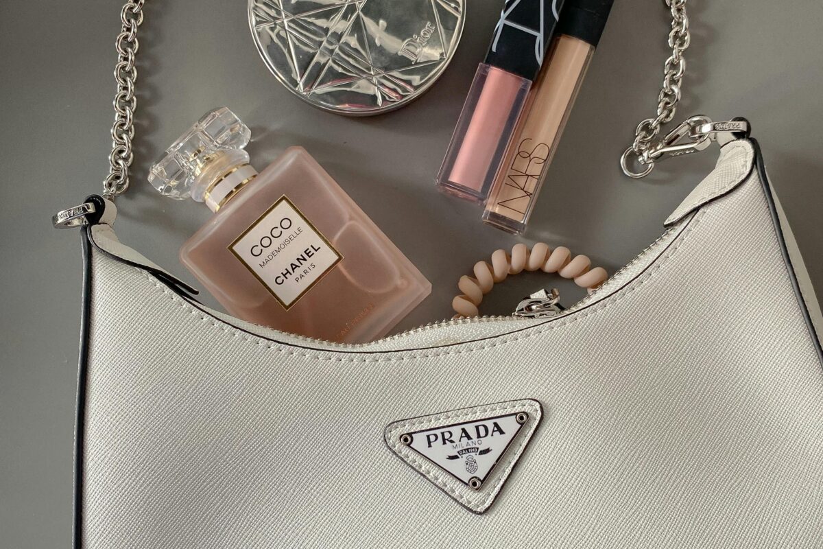 Elegant flatlay featuring a luxury handbag with makeup and perfume.