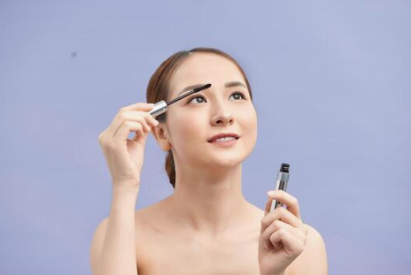 an Asian girl applying eyebrows serum