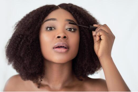 black girl with thick eyebrows applying eyebrows serum